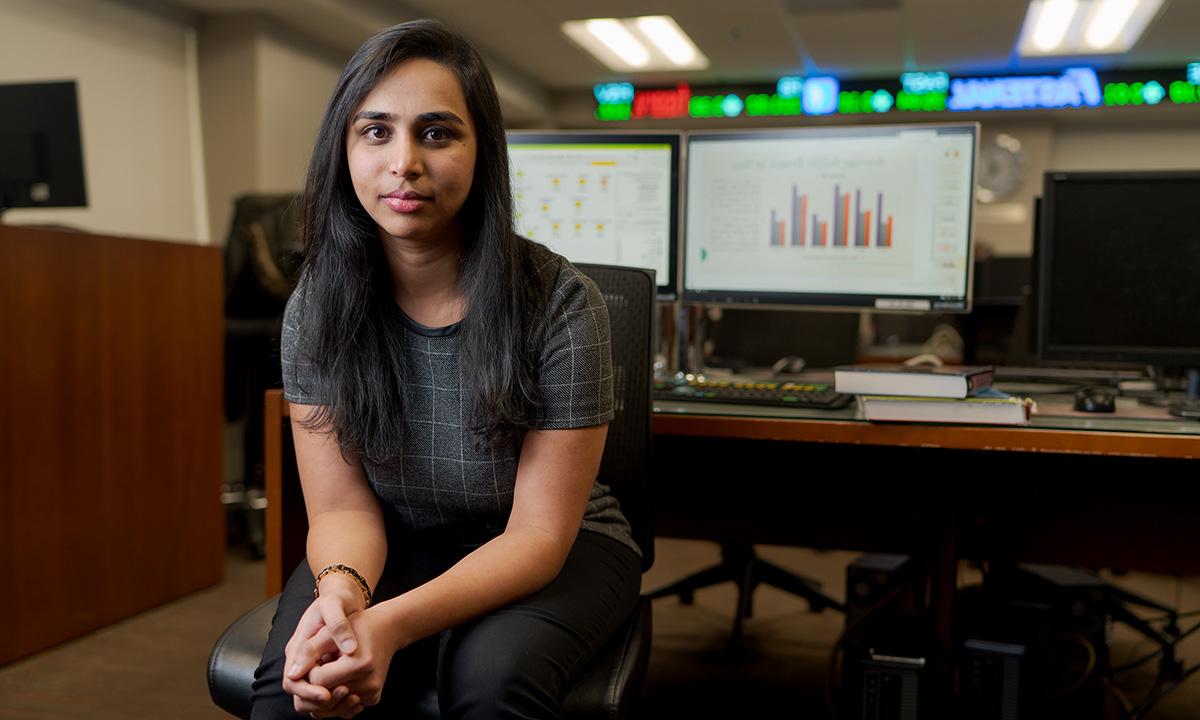 Woman sitting with back to dual-screen computer.